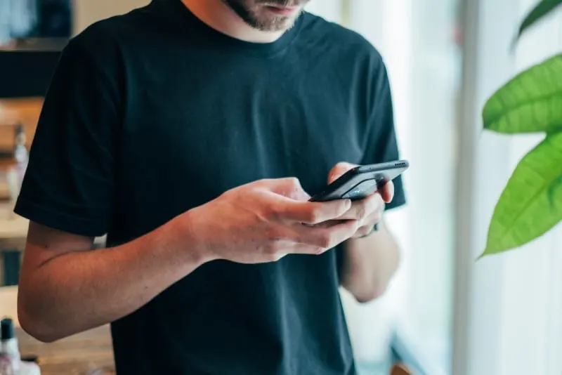 10 signes que votre ex fait semblant d'avoir tourné la page 11 man in black t-shirt using phone