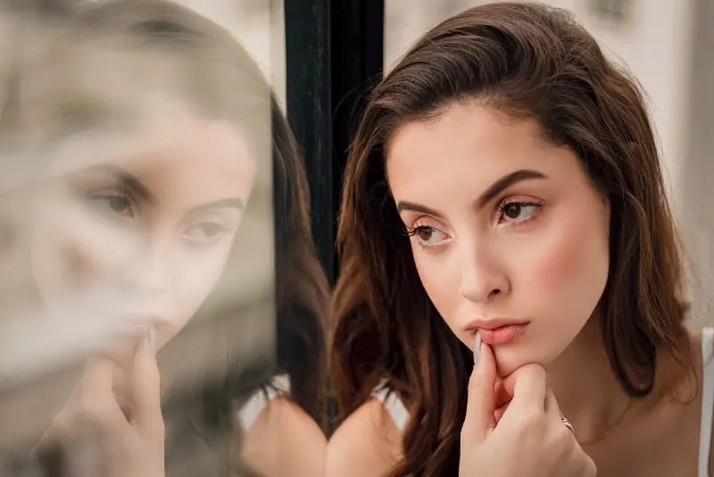 10 signes que votre ex fait semblant d'avoir tourné la page 12 woman sitting by window looking outside