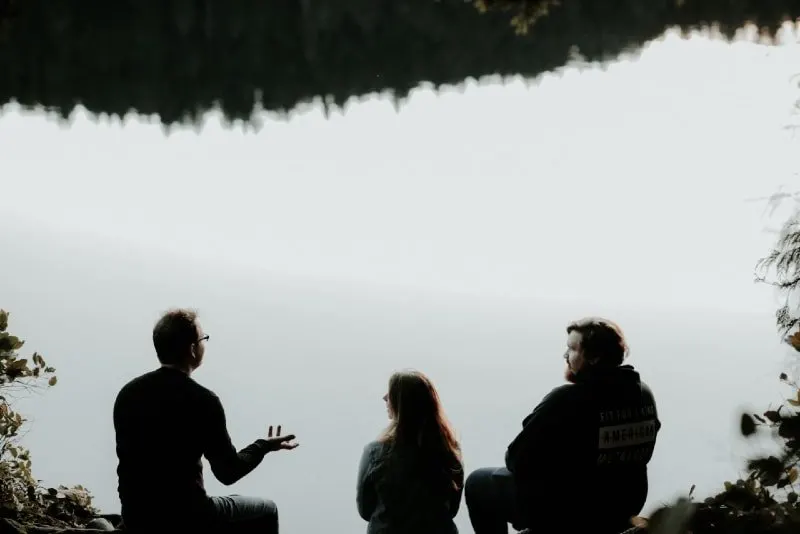 10 signes que votre ex fait semblant d'avoir tourné la page 4 three people sitting near water and talking