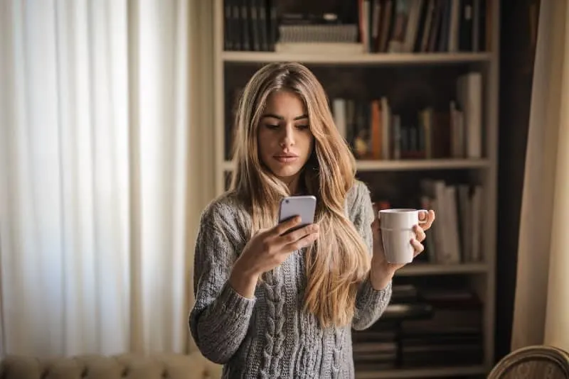 10 signes que votre ex fait semblant d'avoir tourné la page 7 woman in gray sweater looking at phone