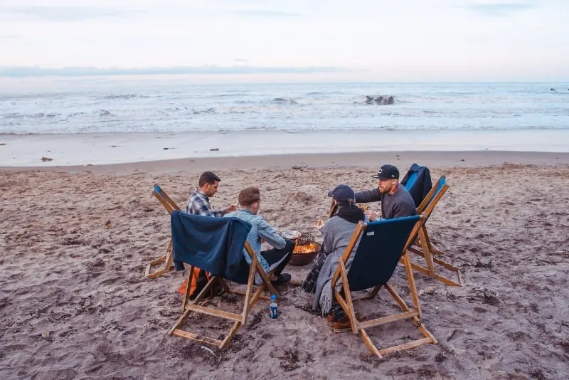 people sitting on beach lounge in front fire pit