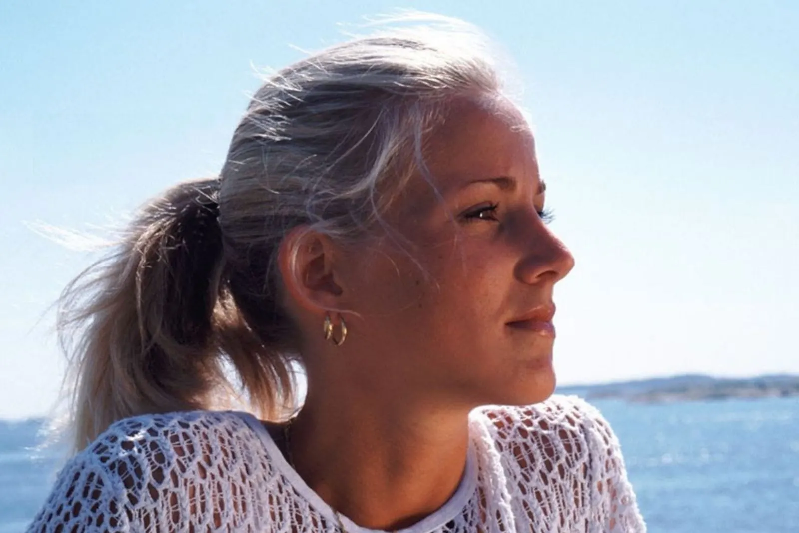 pensive caucasian woman sitting near a body of water with focus on the head