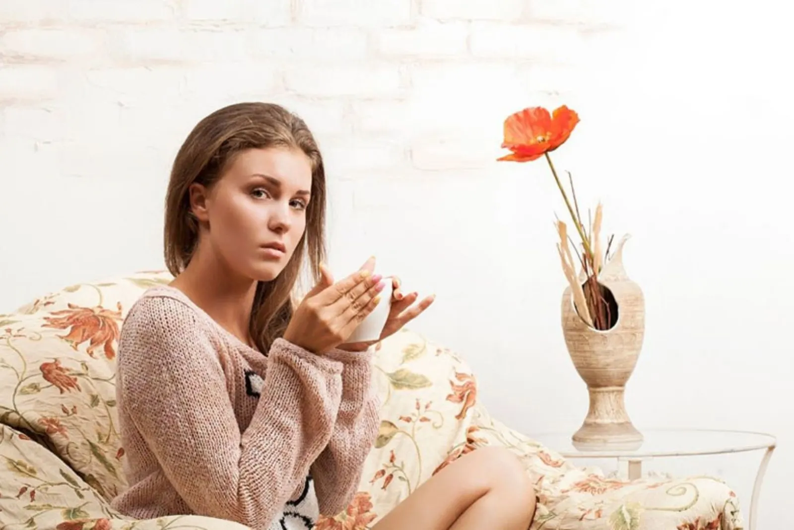 9 étapes cruciales pour se remettre avec son ex 4 woman with a questioning eyes looking at the camera sitting on a couch and drinking a hot beverage