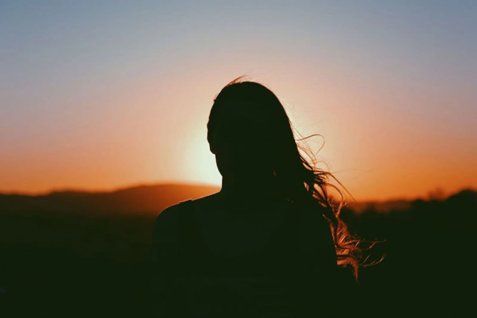 9 étapes cruciales pour se remettre avec son ex 6 silhouette of a woman facing the sunset with hair partly blown by the wind