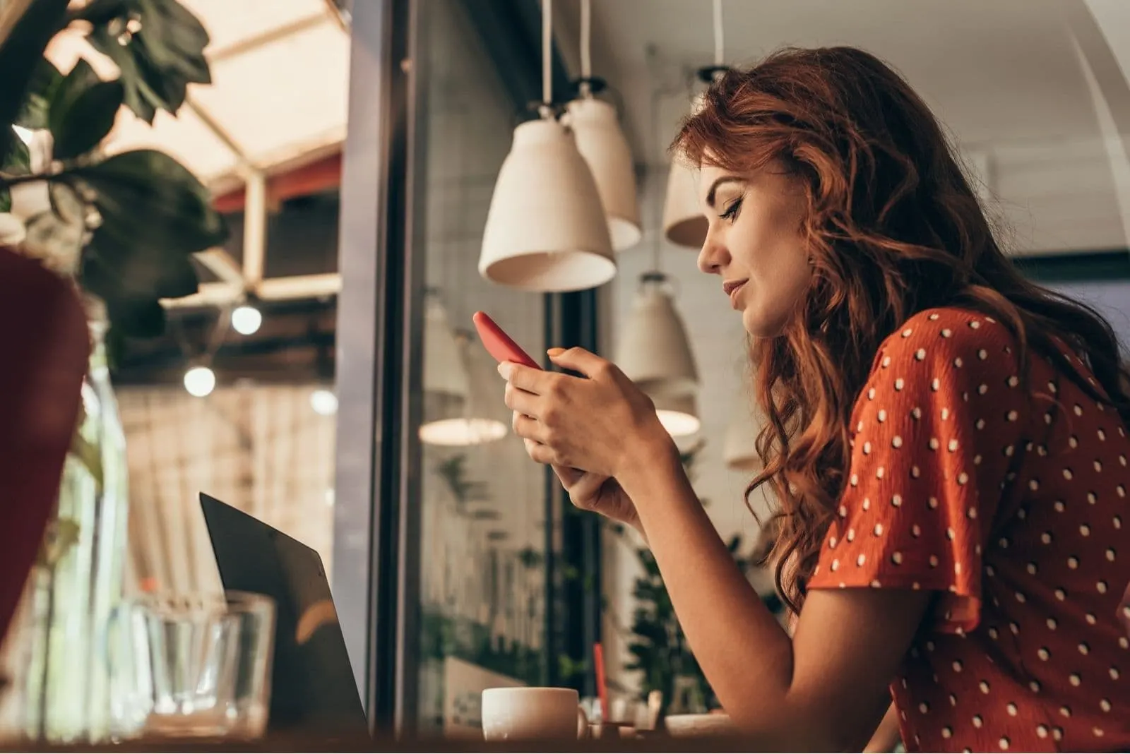 woman checking on smartphone while sitting inside the cafe 