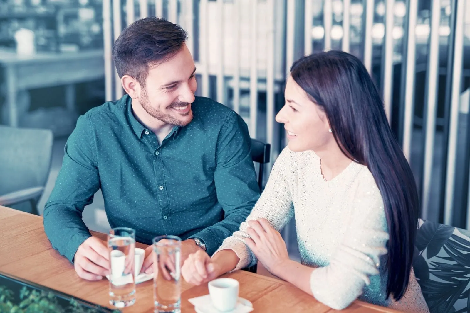 couple talking cheerfully in and ourdoor cafe sitting next to each other