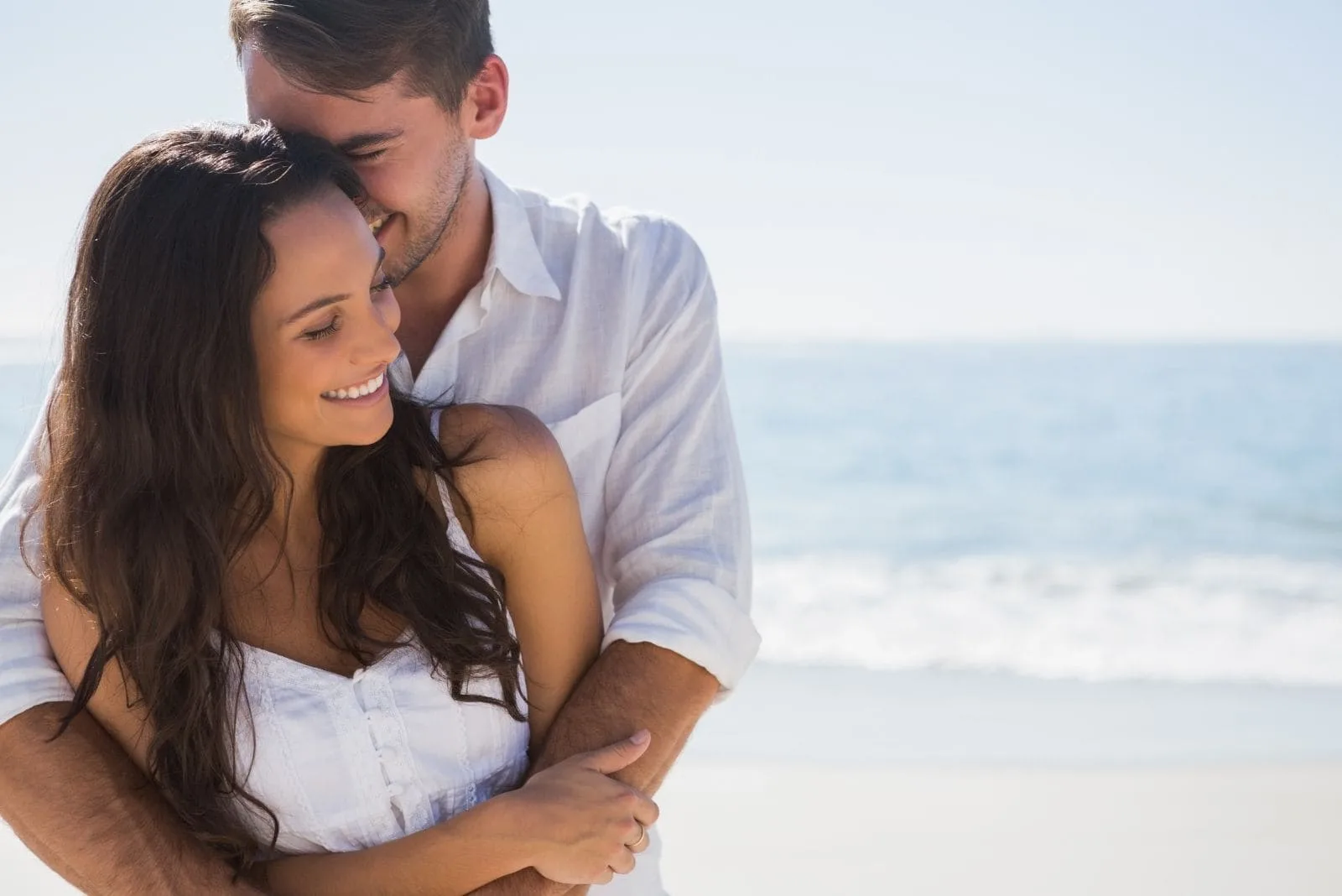 9 étapes cruciales pour se remettre avec son ex 15 romantic man hugging his girlfriend standing in the beach with the sea as the background