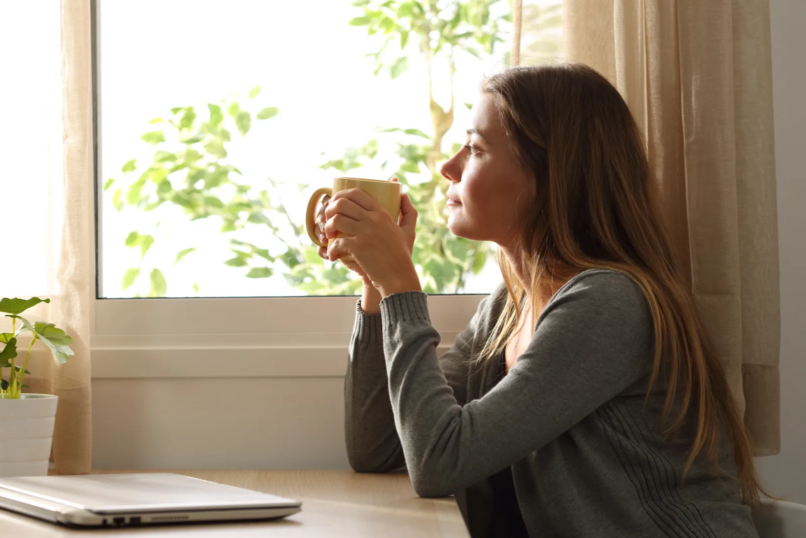 an imaginary woman sits at a table holding a cup in her hand