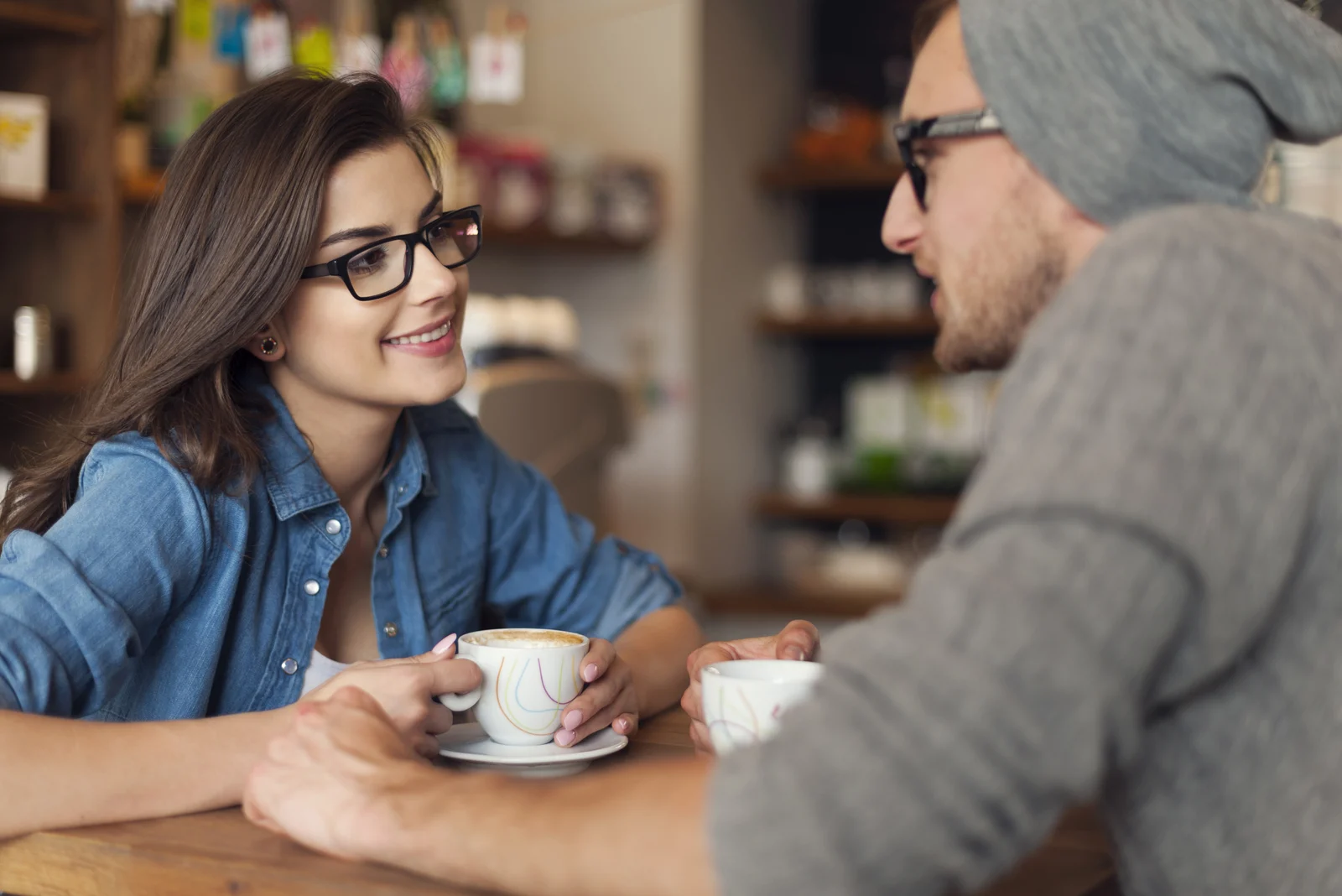 a man and a woman are sitting at a table in a cafe talking