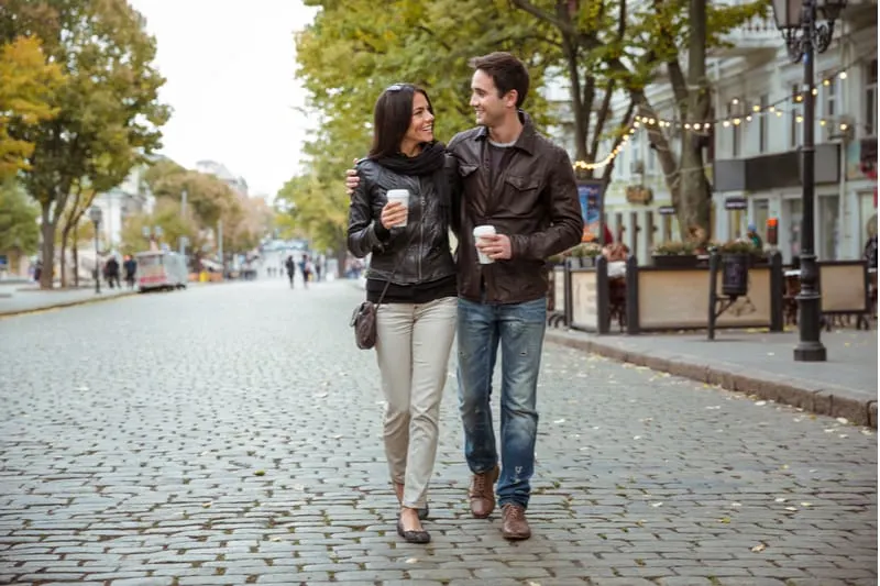 romatic happy couple walking down the street bringing coffee