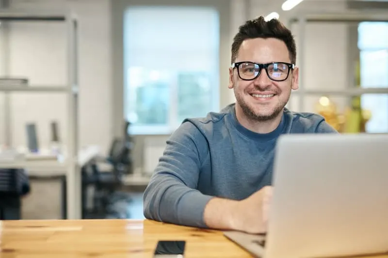 man smiling looking at the camera sitting in his desk inside office