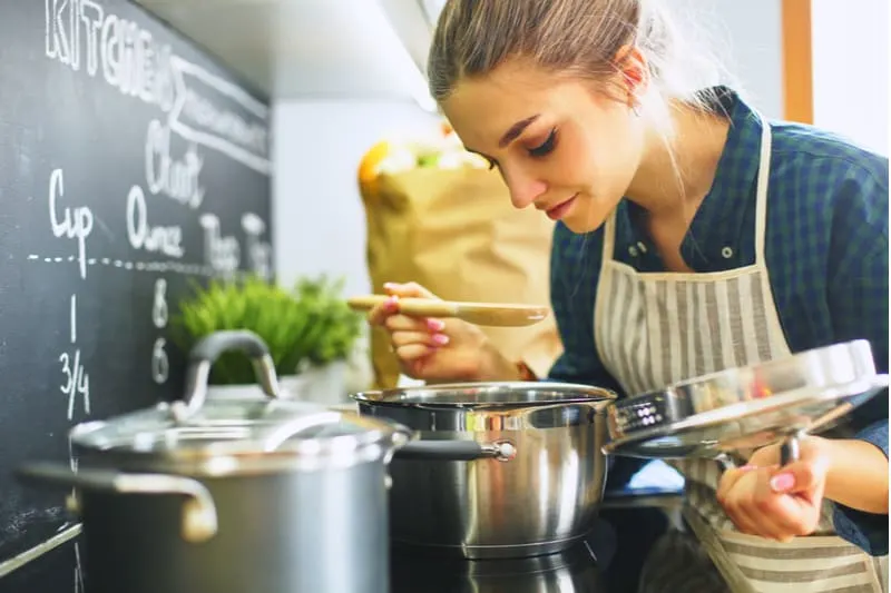 60 des meilleures idées pour complimenter un homme sur sa personnalité 19 young woman cooking in the kitchen smelling the food from the caserole