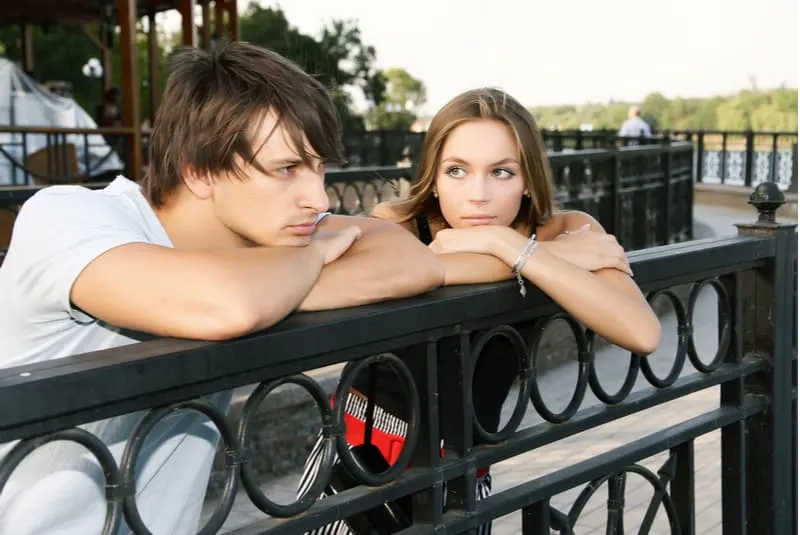 woman looking at an upset man while leaning on the railings