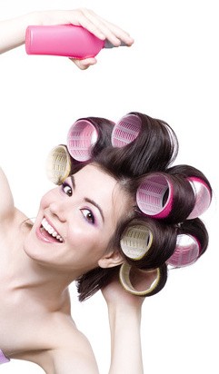 Laughting girl with colorful hair-curlers and hair spray