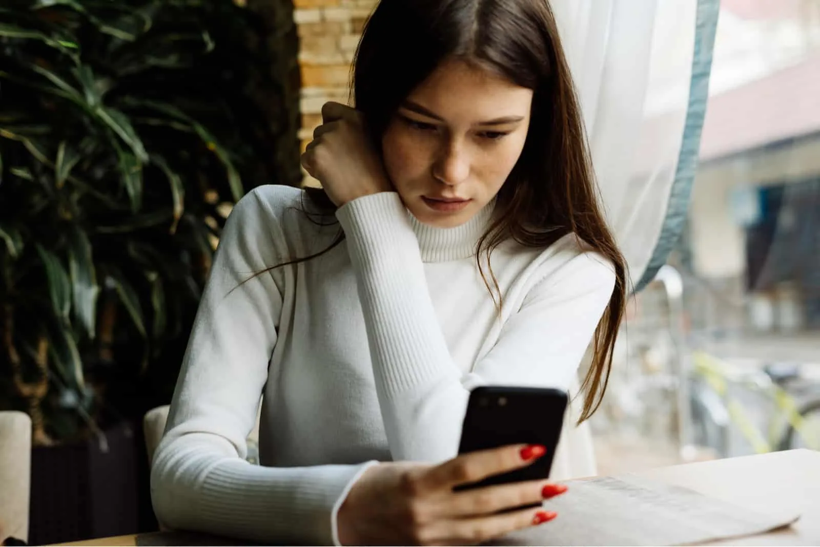 20 signes évidents que votre ex finira par revenir 25 a woman with long brown hair sits at a table and looks at the phone